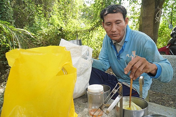 Anh Nguyễn Văn Tý (41 tuổi, ngụ huyện Ba Tri, tỉnh Bến Tre) lấy vội hộp cơm ra ăn lót dạ trước khi tiếp tục công việc