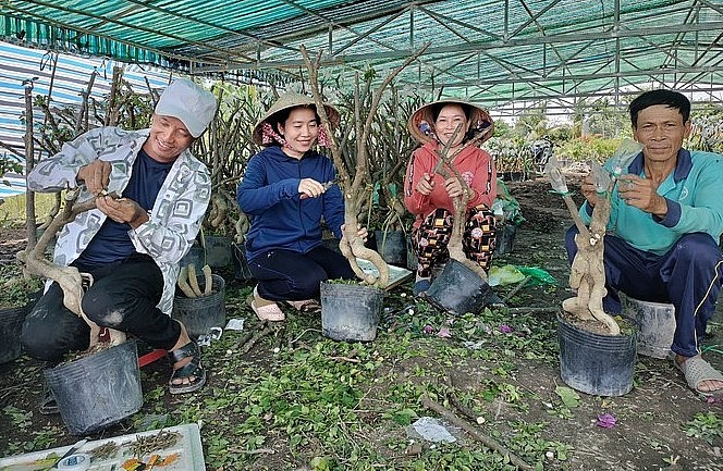 Chị Nguyễn Thị Kim Vân thứ 2 (từ trái) cùng người làm công đang ghép hoa giấy.