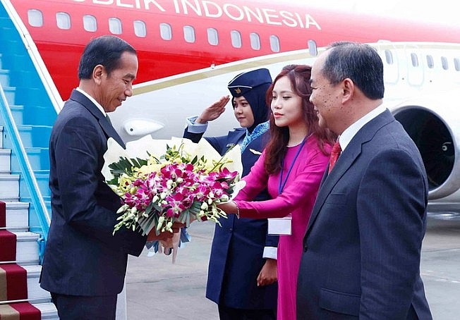Tổng thống Indonesia Joko Widodo nhận bó hoa chào mừng khi đến sân bay Nội Bài chiều 11-1 - Ảnh: TTXVN