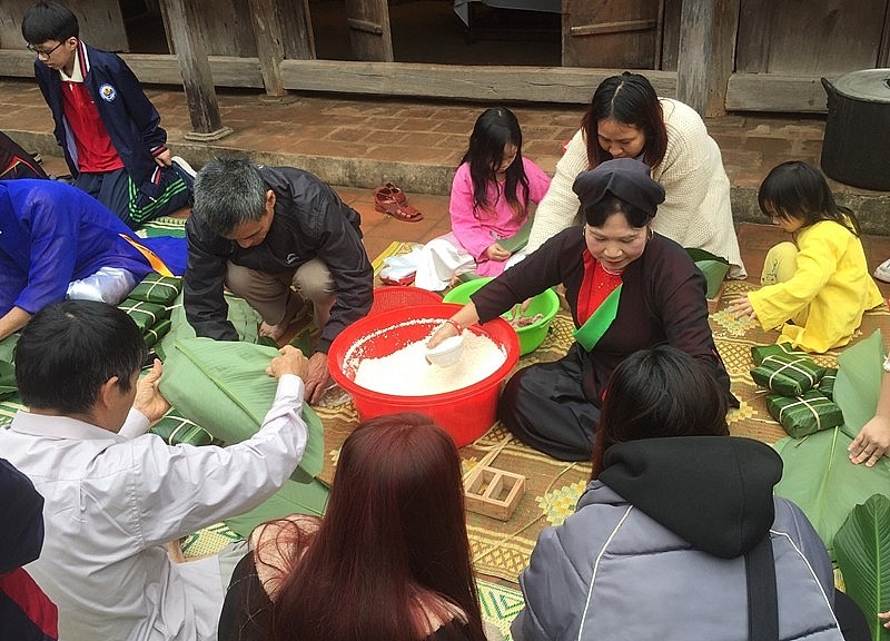 Các nghệ nhân Bắc Ninh hướng dẫn các em nhỏ gói bánh chưng.