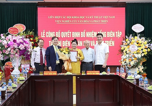 Tân Tổng biên tập Nguyễn Thị Hoa (đứng giữa) nhận quyết định và hoa chúc mừng