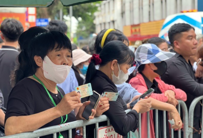 Người dân cầm sẵn căn cước, đứng sau barie đầu phố Nguyễn Công Trứ đợi vào viếng. Ảnh: Hoàng Phương
