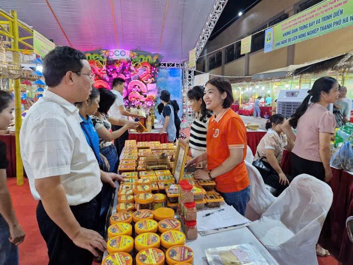 Bà chủ ô mai Vạn Xuân (áo cam) giới thiệu sản phẩm ô mai với khách hàng.