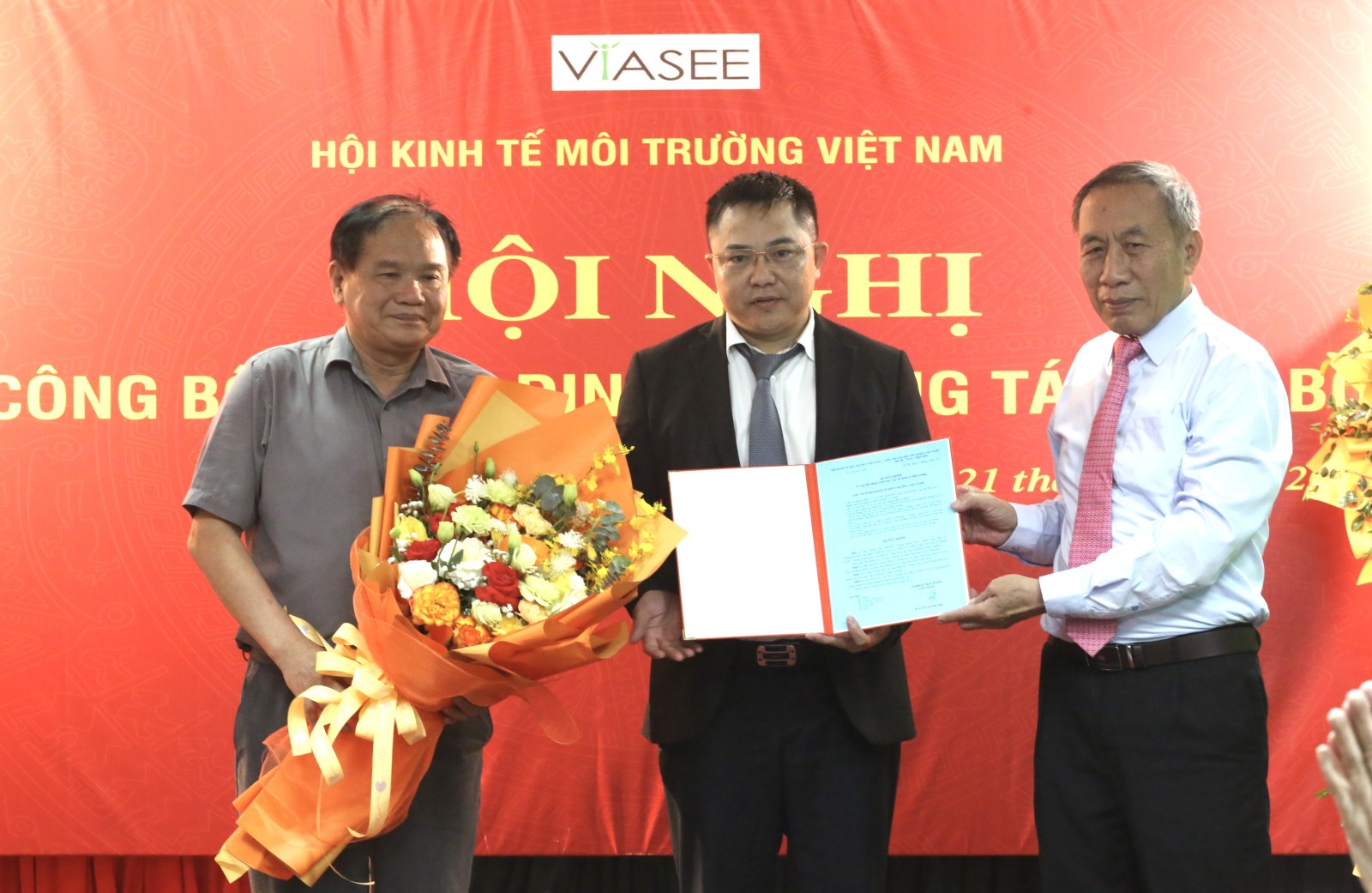 PGS.TS Lưu Đức Hải – Chủ tịch Hội Kinh tế Môi trường Việt Nam (bên phải) và PGS.TS Nguyễn Thế Chinh – Phó Chủ tịch Hội, trao quyết định bổ nhiệm và tặng hoa chúc mừng nhà báo Nguyễn Tường Quân, tân Tổng Biên tập Tạp chí Kinh tế Môi trường.