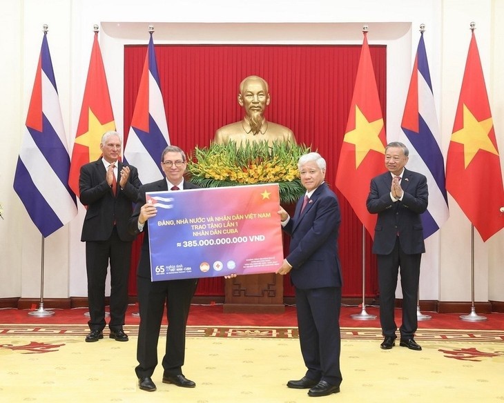 Hai nhà lãnh đạo chứng kiến việc trao tượng trưng lần 1 số tiền Việt Nam ủng hộ Cuba - Ảnh: TTXVN
